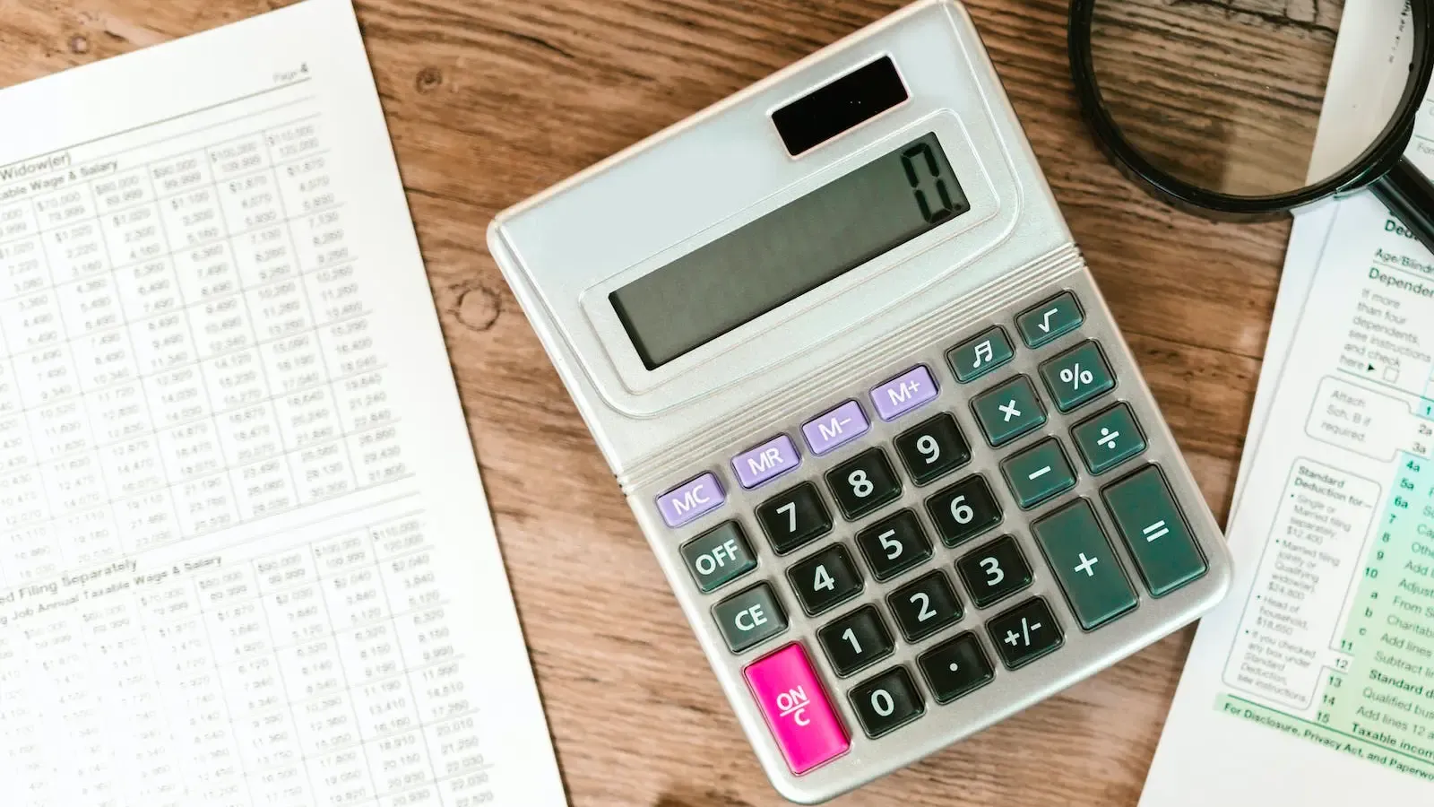 Calculator, magnifying glass, and taxes laid out on the table.