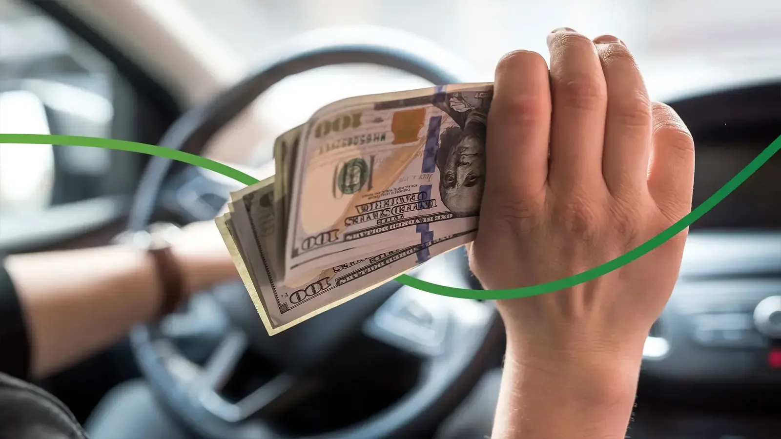 Hand Holding Hundred Dollar Bills While Holding Steering Wheel